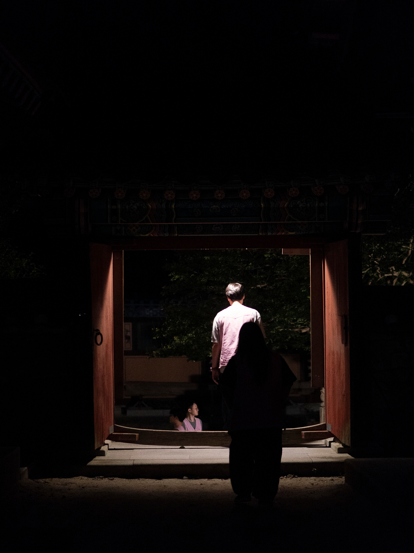 Monk in traditional robes walking through temple doorway in contemplative atmosphere