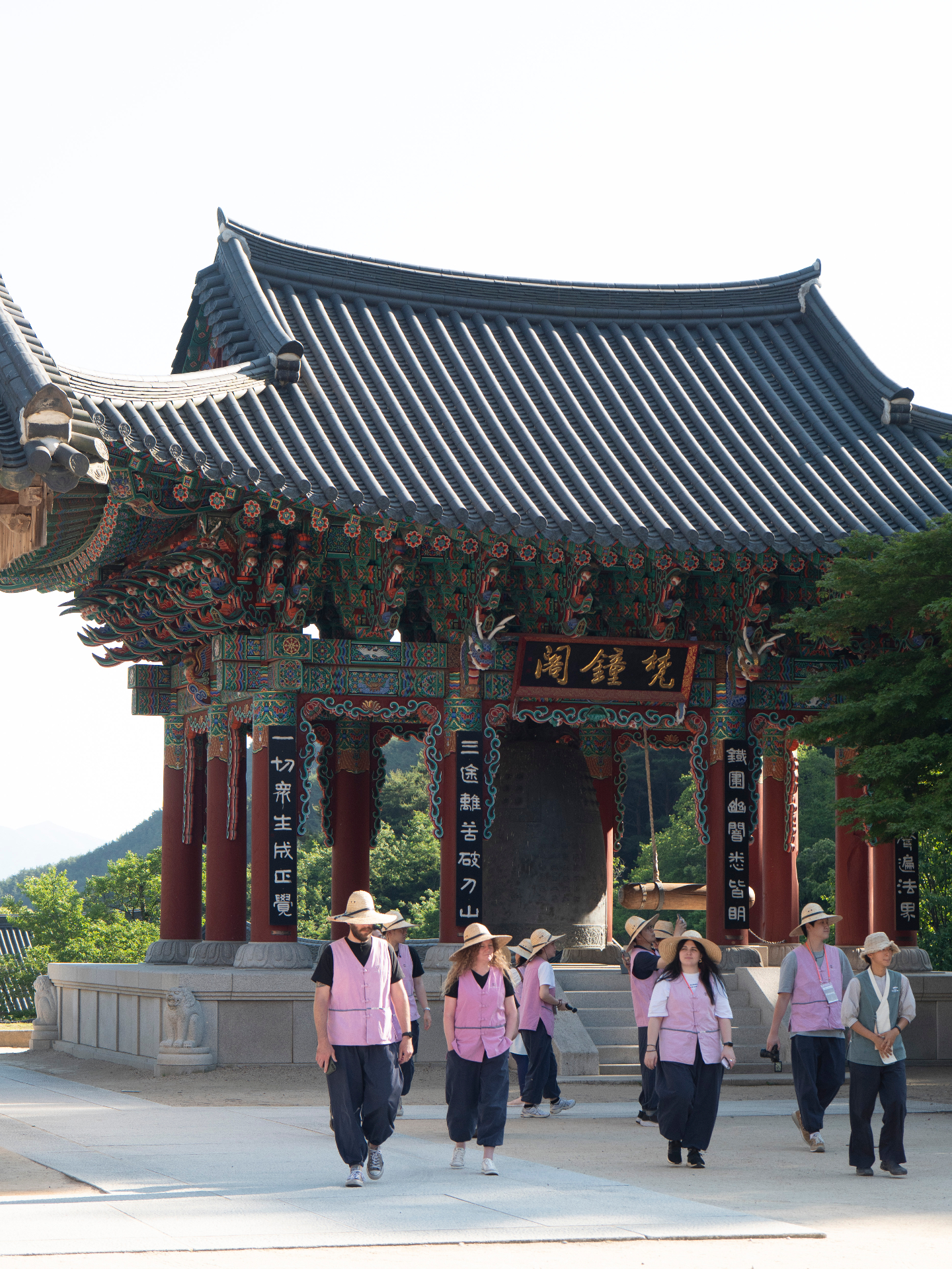 Temple visitors in traditional pink vests gathering at ornate Korean temple entrance